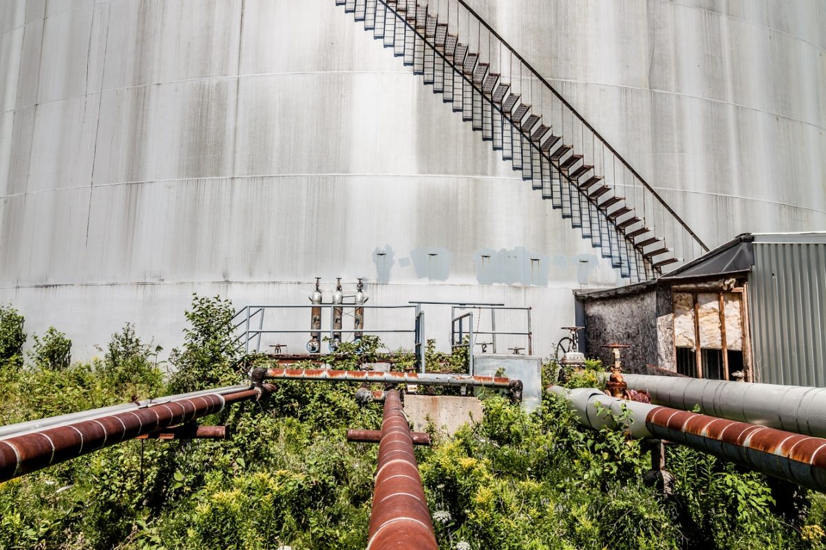 Abandoned Oil Refinery Gas Tank and Rusty Pipeline